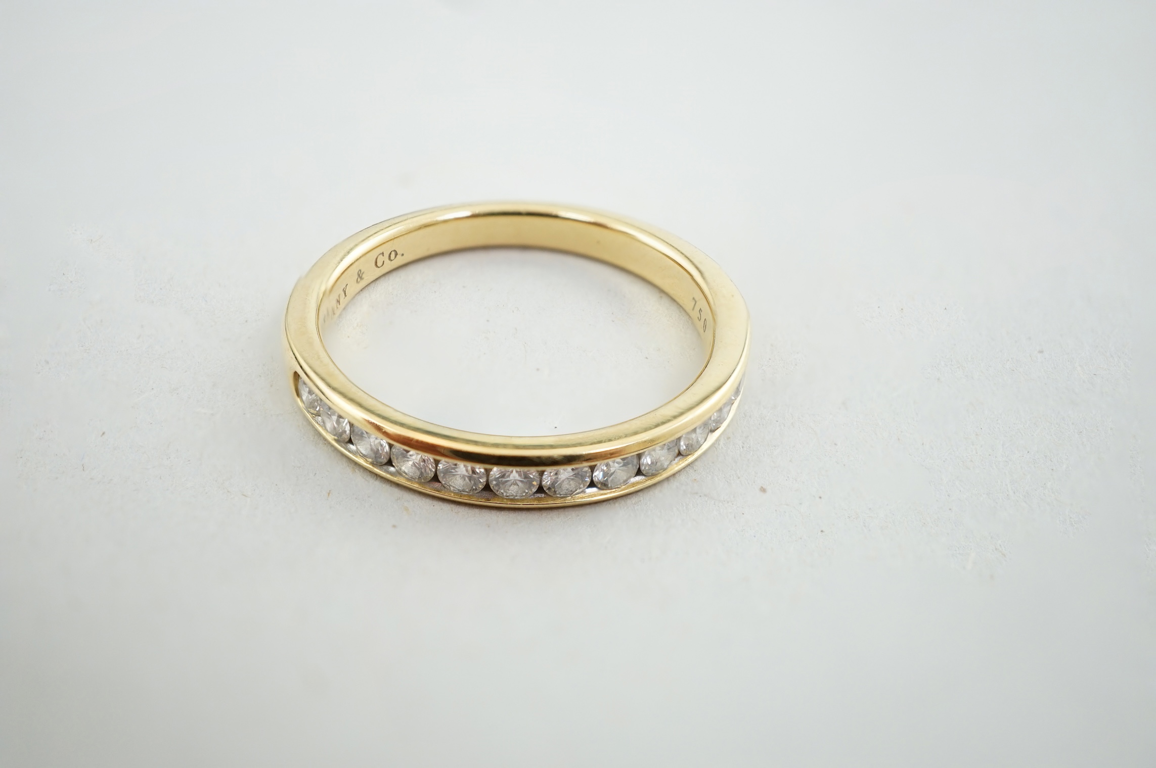 A modern Tiffany & Co 18k gold and channel set thirteen stone diamond half eternity ring